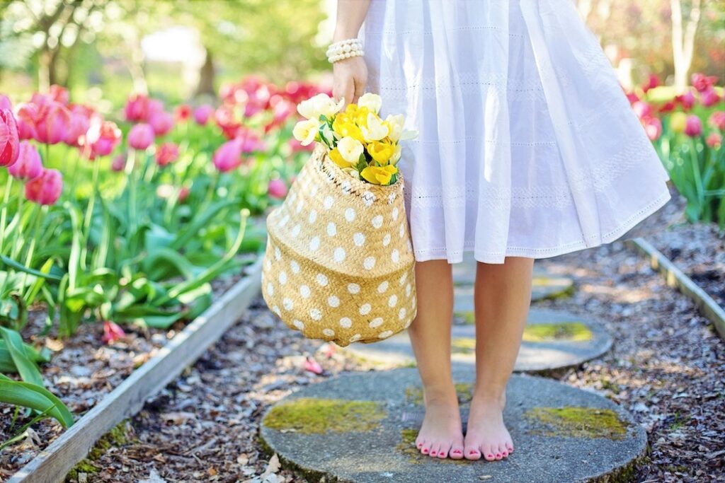 Woman standing barefoot surrounded by seasonal spring flowers